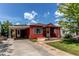 Red bungalow featuring a cozy porch and convenient covered carport, nestled under a bright sky at 753 S Utica St, Denver, CO 80219