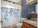 Charming bathroom with a floral shower curtain, granite countertop, wooden vanity, and blue accent wall at 3580 Krameria St, Denver, CO 80207