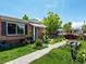 Charming brick home featuring a beautiful landscaped front yard with colorful flowers and a cozy hanging chair at 3580 Krameria St, Denver, CO 80207