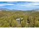 Aerial view of a house nestled among mountains and pine trees at 166 S Rainbow Trl, Evergreen, CO 80439