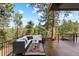 Spacious deck with comfortable seating, glass table, and outdoor rug, surrounded by lush trees and a view at 166 S Rainbow Trl, Evergreen, CO 80439