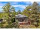 Exterior view of home with deck and hot tub surrounded by tall pine trees at 166 S Rainbow Trl, Evergreen, CO 80439