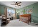 A cozy bedroom features a wooden crib, accent wall with forest animals, and a comfortable upholstered chair at 8372 Bijou Creek Ave, Littleton, CO 80125