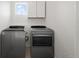 Well-lit laundry room featuring stainless steel washer and dryer, and white cabinets at 8372 Bijou Creek Ave, Littleton, CO 80125