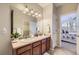 Well-lit bathroom with double sinks, a large mirror, wood cabinets, and a view of the bedroom at 8915 Federal Blvd # 203, Denver, CO 80260
