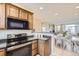 Open-concept kitchen with stainless appliances, wood cabinets, and views of the dining area at 8915 Federal Blvd # 203, Denver, CO 80260
