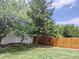 Private backyard with well-maintained lawn, a wooden fence, mature trees, and planting beds at 5695 W 109Th Cir, Westminster, CO 80020