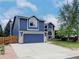 Charming two-story blue home with landscaped front yard and long driveway leading to the garage at 5695 W 109Th Cir, Westminster, CO 80020
