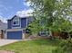 Charming two-story blue home with landscaped front yard and a blue two car garage door at 5695 W 109Th Cir, Westminster, CO 80020