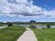 Scenic lake view with walking path, lush green grass, and distant mountain views under a partly cloudy sky at 5695 W 109Th Cir, Westminster, CO 80020