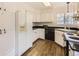 Well-lit kitchen features white cabinets, black appliances, and wood-look flooring, offering a practical cooking space at 5016 S Nelson St # C, Littleton, CO 80127