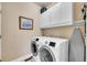Functional laundry room with a washer, dryer, overhead cabinets, and an ironing board at 10452 Rutledge St, Parker, CO 80134