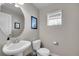Functional powder room with a pedestal sink, toilet, framed mirror, and natural light from a window at 10452 Rutledge St, Parker, CO 80134