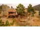 An exterior elevation of a two-story home with a wood deck, a pergola, trees, and wood siding at 26167 De Berry St, Conifer, CO 80433