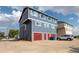 Three-story blue home with red garage doors and siding on a concrete driveway on a partly cloudy day at 711 Elm St, Frederick, CO 80530