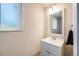 Bright bathroom featuring a vanity with white cabinets, a rectangular mirror, and a frosted window at 8952 W Stanford Ave, Denver, CO 80123