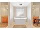 Bright bathroom with a sleek, modern soaking tub positioned between dual vanities and a tiled privacy window at 507 Ulster Way, Denver, CO 80230