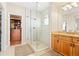 Bathroom featuring a glass enclosed shower, wooden vanity, and doorway to walk-in closet at 507 Ulster Way, Denver, CO 80230