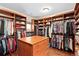 Large walk-in closet with custom shelving, hanging racks, and center island with wooden drawers at 507 Ulster Way, Denver, CO 80230