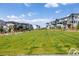 A large green lawn bordered by townhouses and trees offers a serene community space on a sunny day at 1500 Sun Way, Lafayette, CO 80026