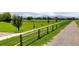 Gravel walking path surrounded by green grass and a wooden fence leading towards distant trees and a peaceful meadow at 1500 Sun Way, Lafayette, CO 80026
