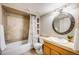 Well-lit bathroom featuring a tub with patterned tile surround and a round mirror over a wood vanity at 3889 S Fraser St, Aurora, CO 80014
