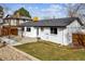 View of the home's white painted brick exterior, patio with pergola, and well-maintained backyard at 13586 W Warren Cir, Lakewood, CO 80228