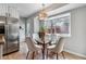 Bright dining area features a glass table, plush chairs, wood floors and a window with natural light at 13586 W Warren Cir, Lakewood, CO 80228