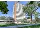 Tall apartment building with many balconies, a fenced yard, mature trees, and sidewalk at 1250 N Humboldt St # 202, Denver, CO 80218