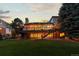 Exterior view of a home with a well-lit deck, stairs, and a spacious green lawn at dusk at 9232 Rockport Ln, Highlands Ranch, CO 80126