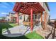 Outdoor patio with grill, table, and seating under a red pergola with artificial grass surround at 15246 W 94Th Ave, Arvada, CO 80007