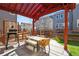 Outdoor patio with a grill, table, and seating under a red pergola in a fenced backyard at 15246 W 94Th Ave, Arvada, CO 80007