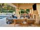 Expansive covered outdoor patio with stone fireplace, comfortable seating, and view to surrounding landscaped areas at 4603 S Denice Dr, Cherry Hills Village, CO 80111
