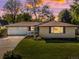 Charming single-story home with a manicured lawn, inviting front porch, and a two-car garage under a colorful evening sky at 6943 Oak Way, Arvada, CO 80004