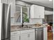 Well-lit kitchen featuring stainless steel appliances, granite countertops, and stylish white cabinets at 6943 Oak Way, Arvada, CO 80004