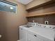 Laundry room features a side-by-side washer and dryer, window and wood shelving at 6943 Oak Way, Arvada, CO 80004