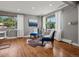 Bright living room with hardwood floors, two blue chairs, large windows, and sheer curtains at 6943 Oak Way, Arvada, CO 80004