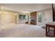 Bright living room featuring a stone fireplace, large windows offering views of greenery, and neutral-toned walls and carpet at 9402 W 89Th Cir, Broomfield, CO 80021