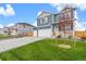 Well-maintained front yard of a blue, two-story home with three-car garage and a white porch at 262 Chardon Ave, Brighton, CO 80601