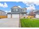 Blue two-story home with a three-car garage, a charming porch, and a well-manicured front lawn at 262 Chardon Ave, Brighton, CO 80601
