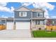 Charming two-story blue home featuring a three car garage, small porch, and manicured lawn at 262 Chardon Ave, Brighton, CO 80601