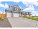 Two-story home with blue siding, three-car garage, long driveway and manicured lawn under a cloudy sky at 262 Chardon Ave, Brighton, CO 80601