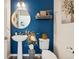 Stylish half-bathroom with blue walls, pedestal sink, decorative mirror, and tasteful decor at 749 Bishop Pine Way, Castle Rock, CO 80104