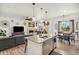 Open-concept living room featuring a kitchen island, gray sofa, fireplace, and decorative wall art at 749 Bishop Pine Way, Castle Rock, CO 80104