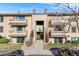 A view of the building's exterior shows stairs to the upper level, mature landscaping, and nearby parking at 430 Zang St # 4-301, Lakewood, CO 80228