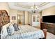 Bright primary bedroom with en suite bathroom access, coffered ceiling, decorative french doors and a large TV at 9164 E Lost Hill Trl, Lone Tree, CO 80124