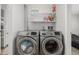 Laundry room with modern, front-load washer and dryer and open shelving for storage at 2101 S Victor St # C, Aurora, CO 80014
