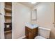 Bathroom with single sink vanity, mirror, toilet, and built-in shelving unit for storage at 2446 S Vaughn Way # A, Aurora, CO 80014