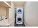 Laundry room with stacked washer/dryer, utility sink, and dark tiled floor at 2446 S Vaughn Way # A, Aurora, CO 80014