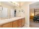 Bright bathroom with a vanity, neutral countertops, wood cabinets, and access to the main bedroom at 3806 S Dawson St, Aurora, CO 80014